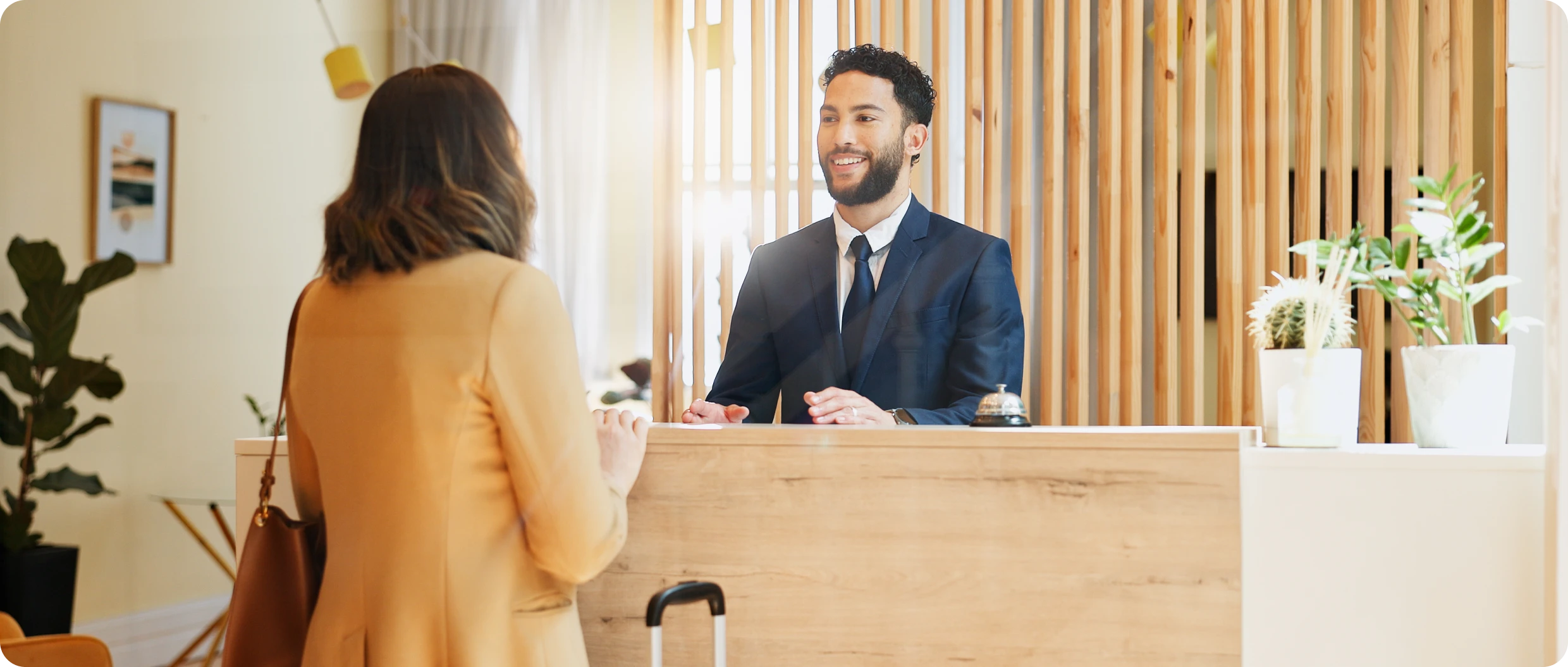 Woman checking in at hotel reception desk.