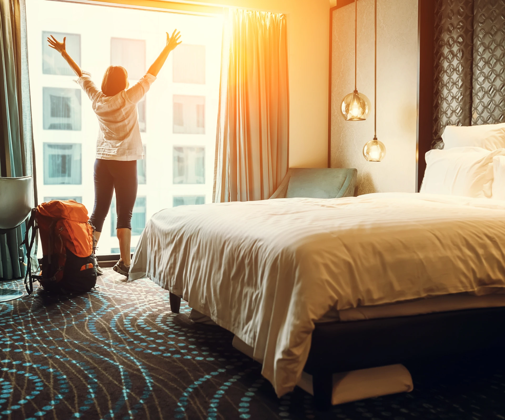 Person stretching in a sunlit hotel room.